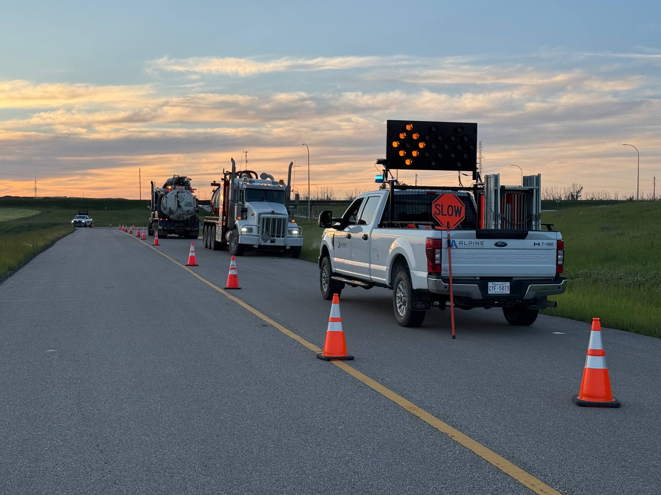 Alpine traffic control truck and arrow board protecting a lane closure at dusk